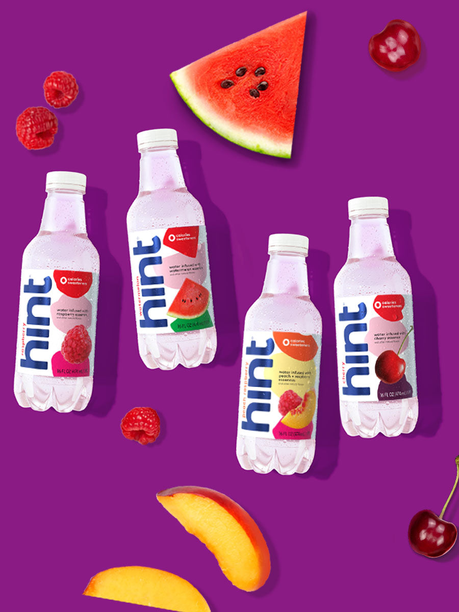 A collage of 4 hint water flavors laid on top of a purple background with various fruits around them.