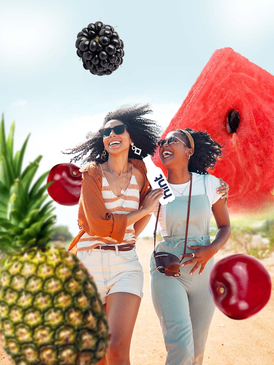 A collage of two women walking on a trail holding a bottle of hint water. There are oversized fruit graphics in the collage photo.