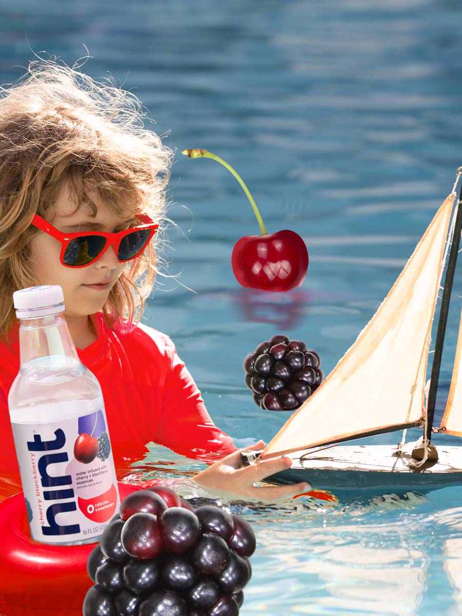 A collage of a girl playing with a sail boat in the water with various fruit pieces and a hint bottle in the water.