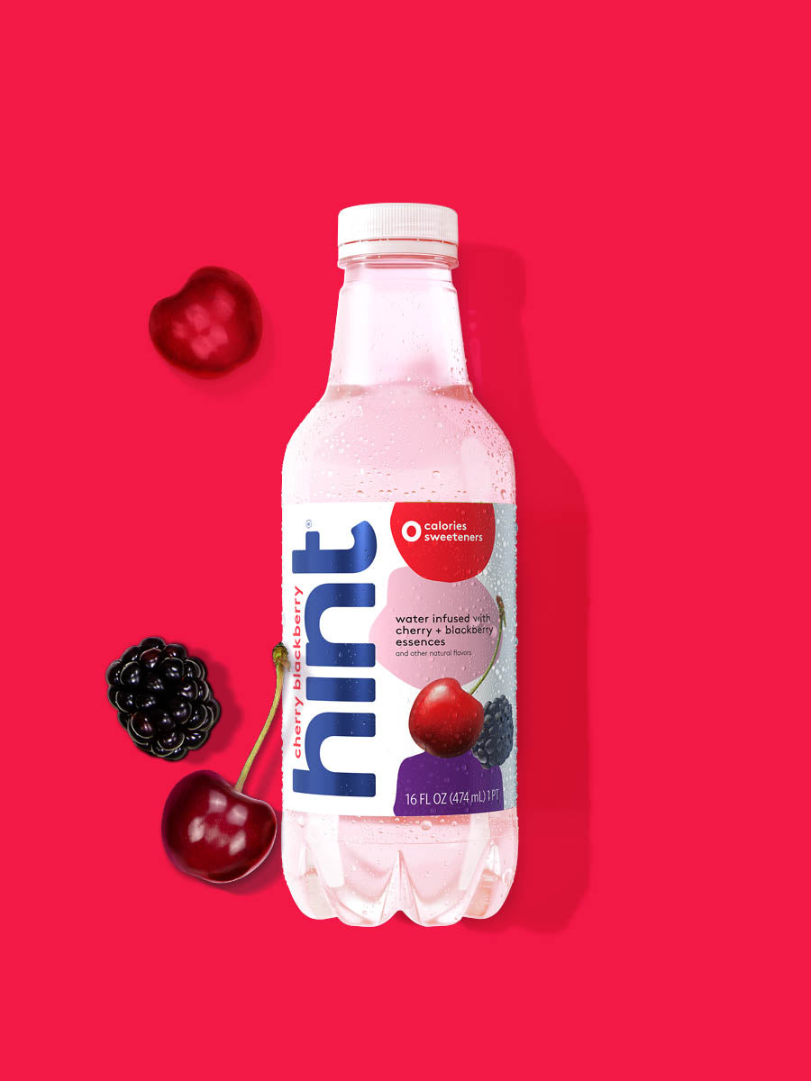 A bottle of Cherry Blackberry hint water on a red background.