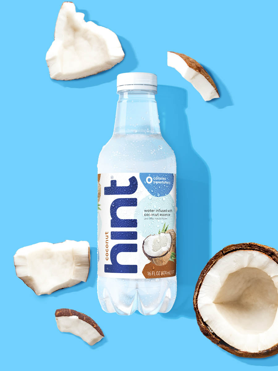 A bottle of Coconut hint water on a blue background. There are various fruit pieces in the background surrounding the bottle.