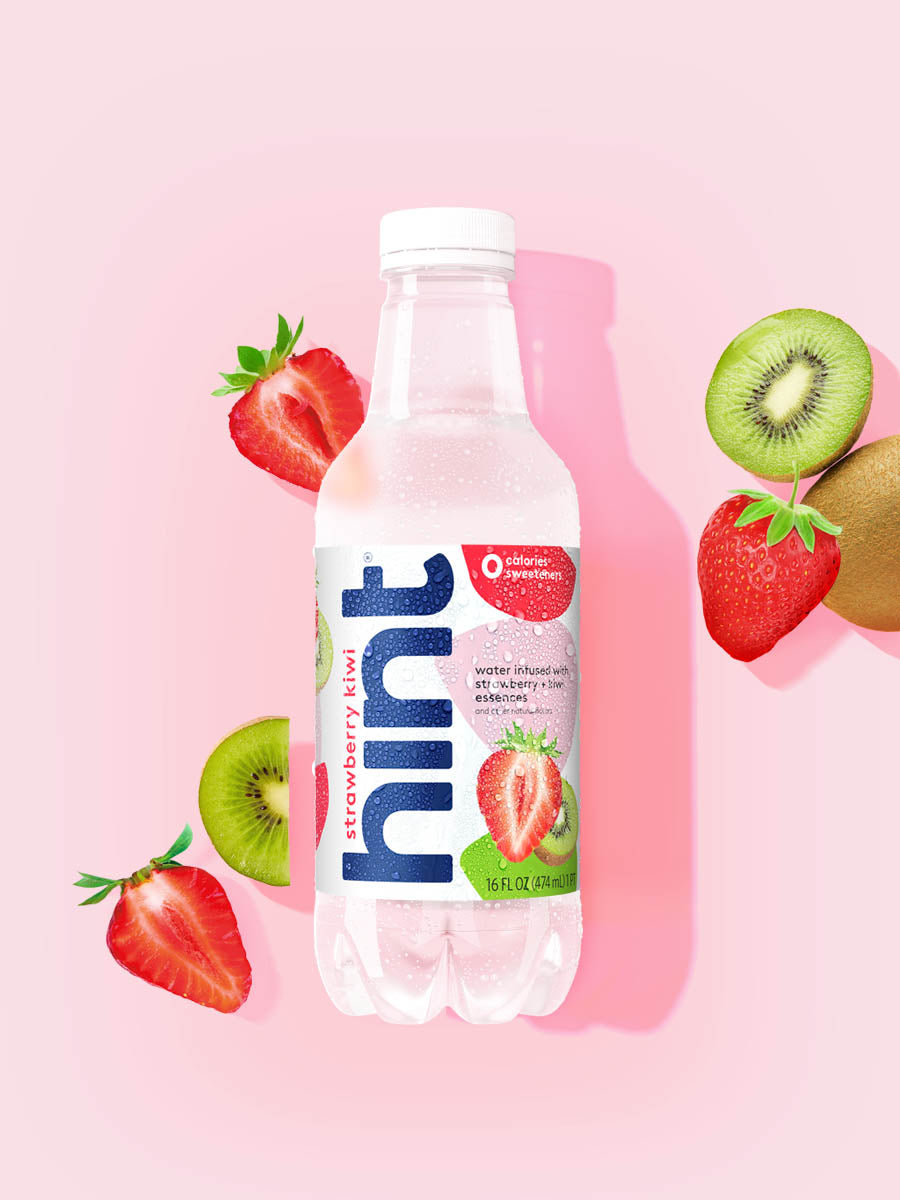 A bottle of Strawberry Kiwi hint water on a light pink background. There are various pieces of these fruits alongside the bottle.