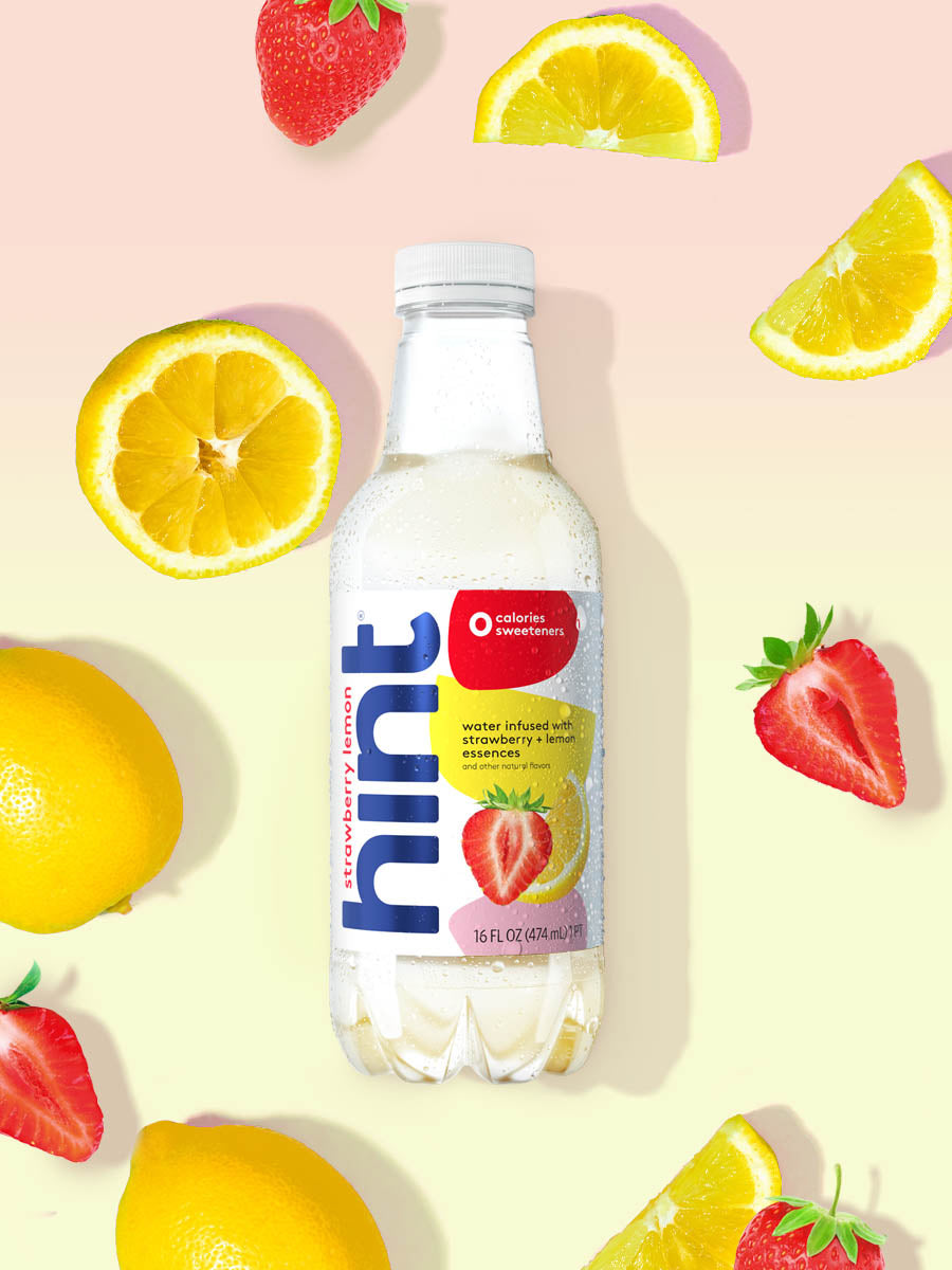A bottle of Strawberry Lemon hint water on a light pink and yellow background. There are various fruit pieces in the background surrounding the bottle.