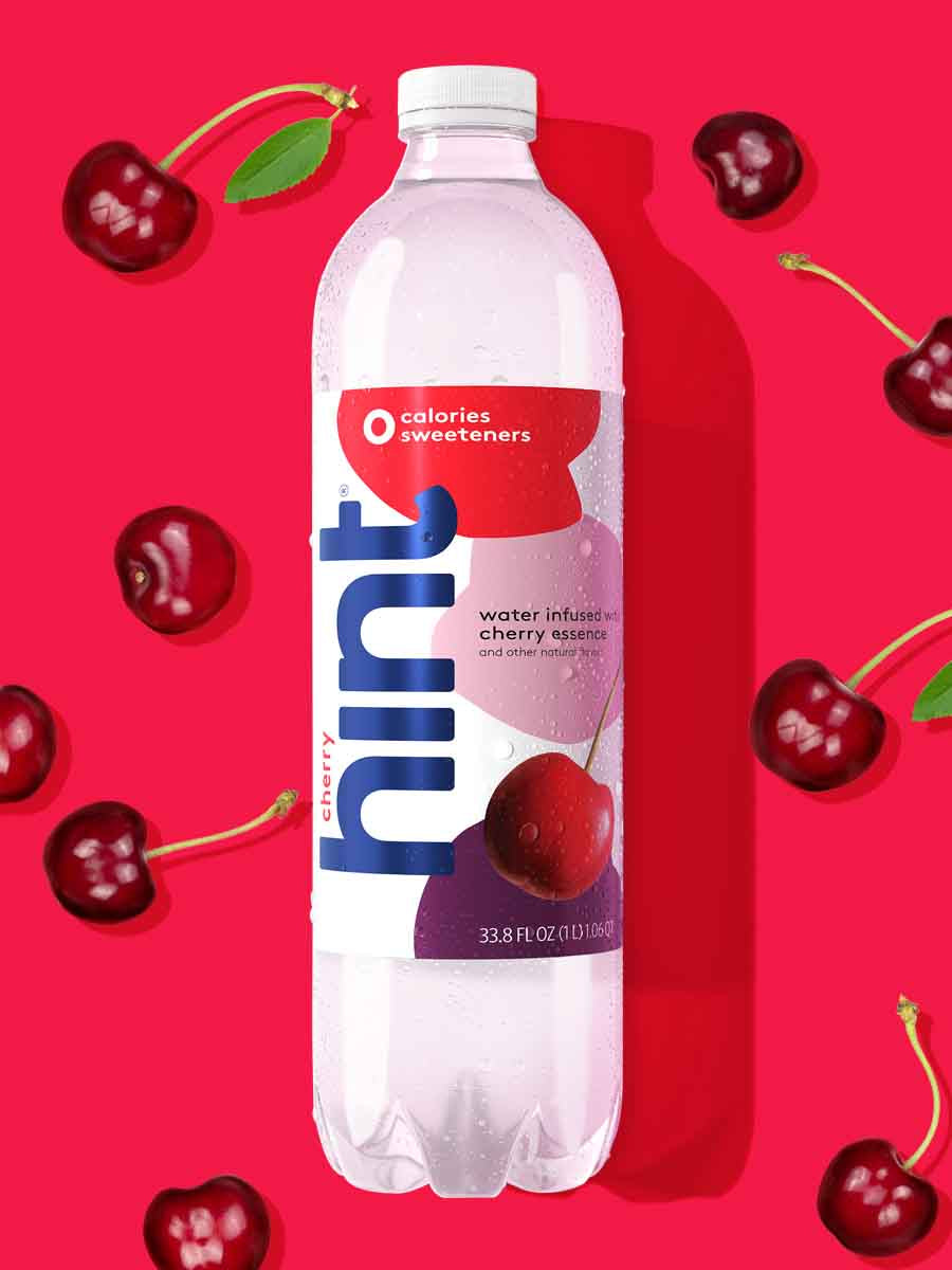 A 1L bottle of cherry hint water on a red background. There are various cherry fruit pieces around the bottle.