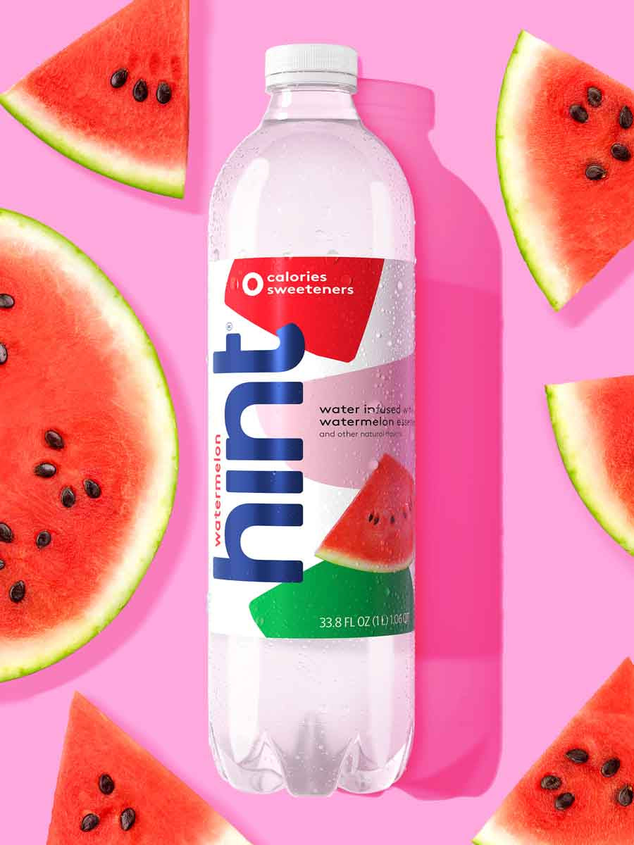 A 1L bottle of watermelon hint water on a yellow background. There are various watermelon fruit pieces around the bottle.