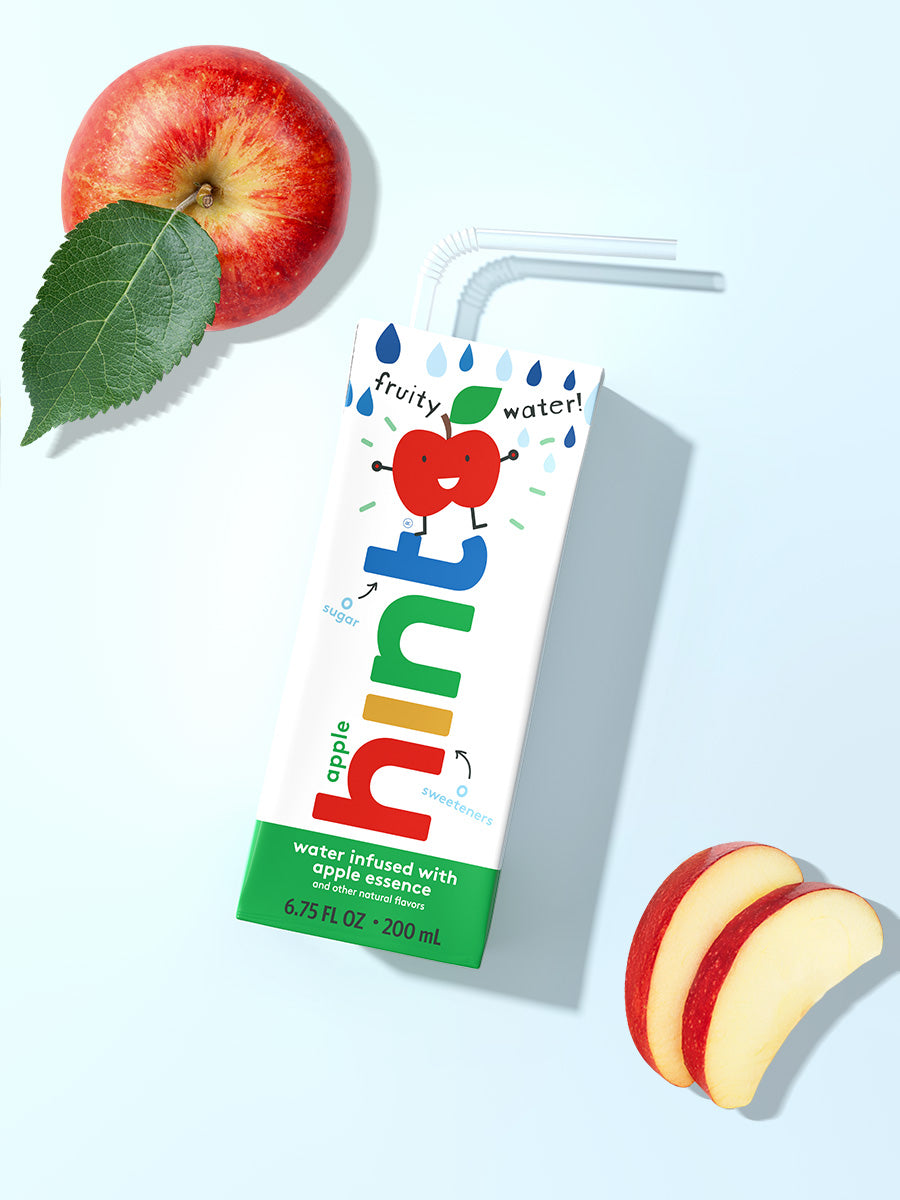 A hint kids water box on a light blue background. It is apple flavored so there is a whole apple and slices in the photo as well.