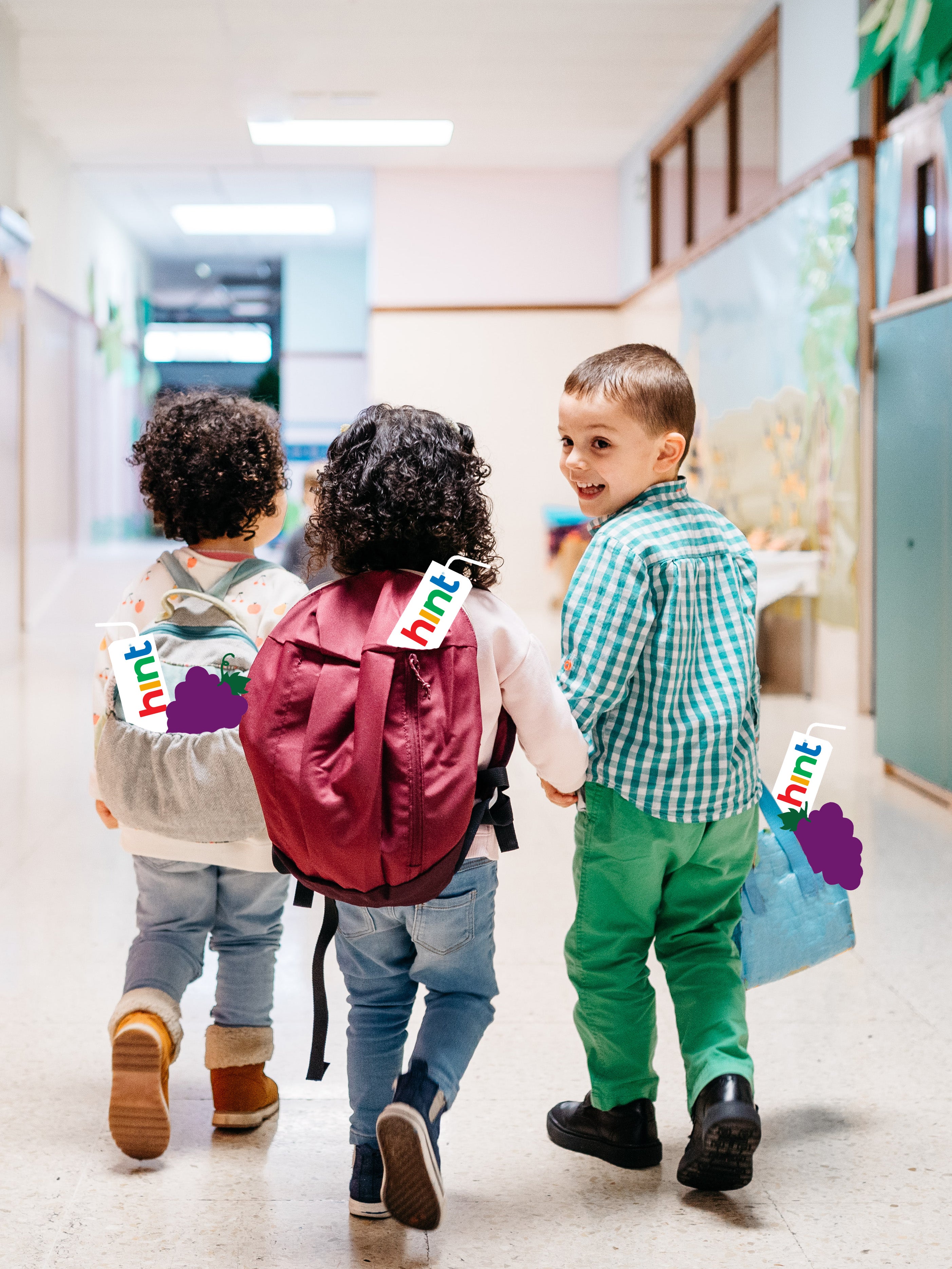 A group of young kids walking the halls of school with hint kids water boxes coming out of their backpacks.