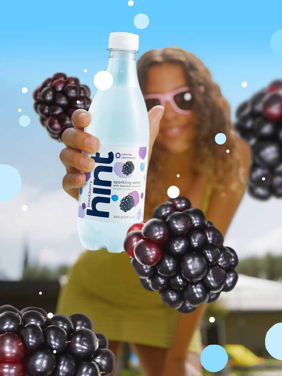 A graphic collage of a woman holding a bottle of blackberry sparkling hint water with oversized blackberries around her.